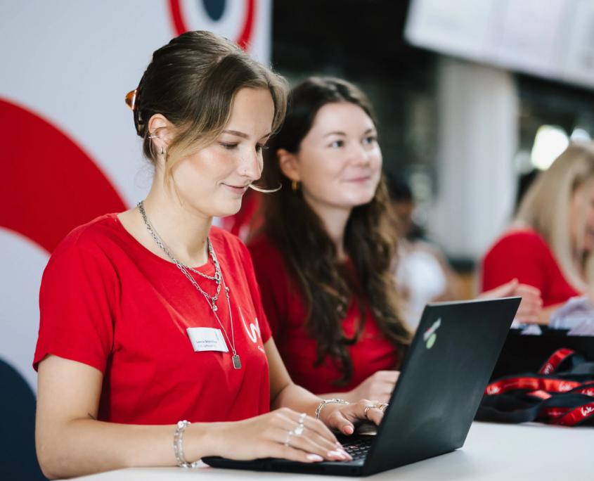 Aufnahme des Empfangsbereichs mit Mitarbeiterinnen der CAS Software AG bei der Registrierung der Besucher am Laptop.