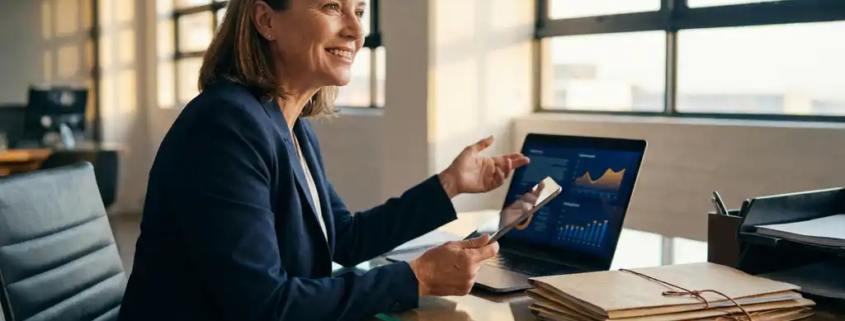 Geschäftsperson analysiert Kundendaten-Dashboard auf leuchtendem Laptop an modernem Bürotisch mit warmem Nachmittagslicht.