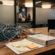Verwirrtes Netzwerkkabel-Gewirr auf Schreibtisch neben ERP-Implementierungsordner, Haftnotizen und Kaffeetasse in IT-Beratungsbüro.