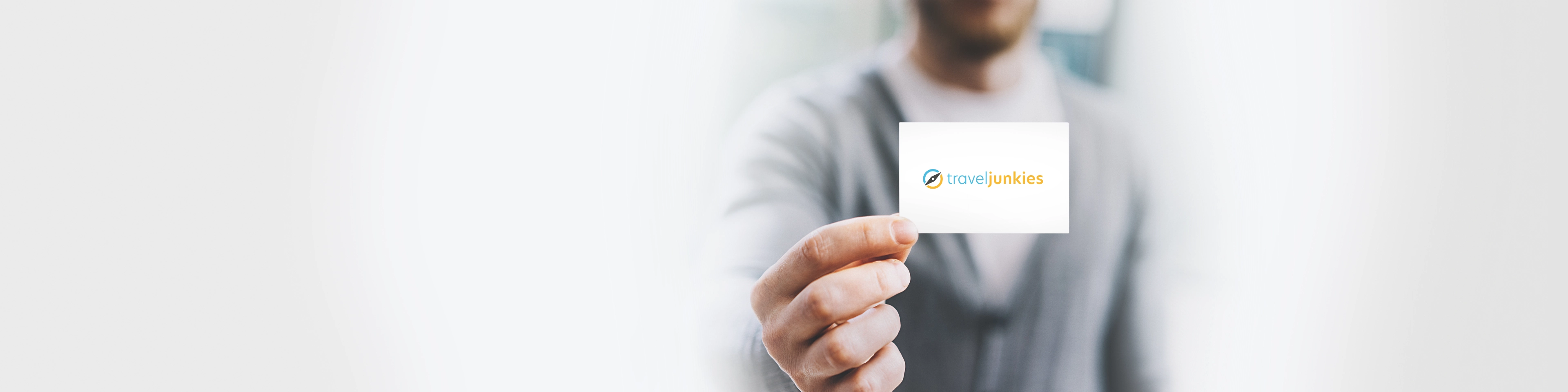 Mann hält eine Visitenkarte in die Kamera – auf der Karte das Logo des Unternehmens traveljunkies GmbH