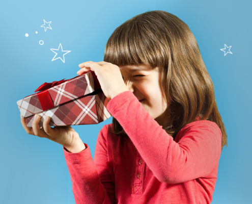 Bild eines Mädchens in rotem Shirt und schulterlangen braunen Haaren vor himmelblauem Hintergrund, welches neugierig den Deckel einer rot karierten Geschenkeschachtel mit roter Satinschleife öffnet. Links und rechts neben ihrem Kopf verteilt schweben weiße illustrierte Sterne in verschiedenen Größen.